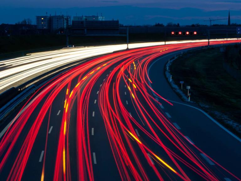 Unzählige Autos fahren bei Nacht auf einer Autobahn und erzeugen rote und gelbe Lichtspuren.