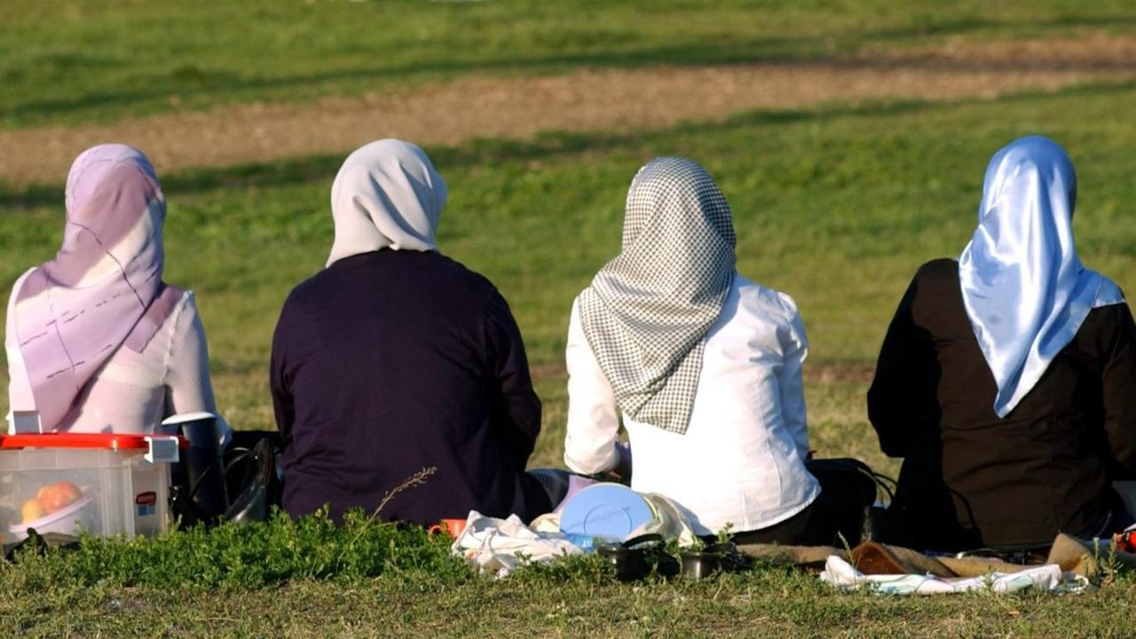 Sie sehen vier Frauen mit Kopftuch auf einer Wiese im Görlitzer Park in Berlin.