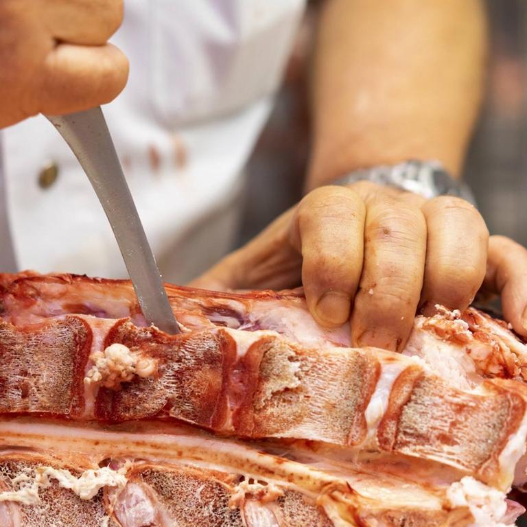 Das Foto zeigt einen Schlachter, der Fleisch schneidet (Symbolfoto).