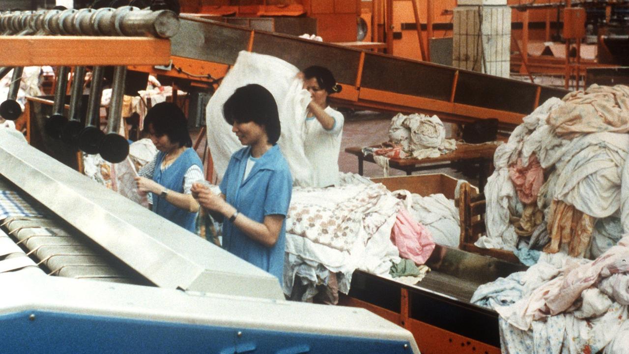 Vietnamesinnen stehen am 26.1.1990 inmitten von Wäschebergen im Kombinat REWATEX in Berlin.