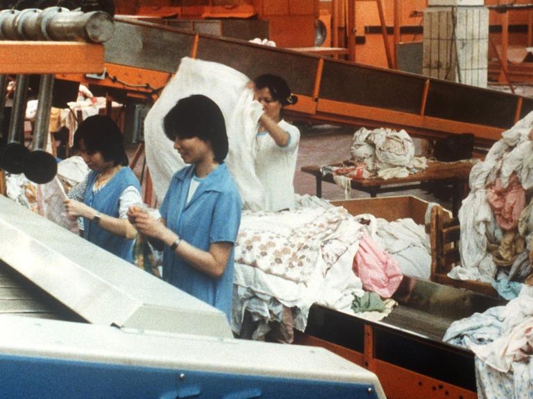 Vietnamesinnen stehen am 26.1.1990 inmitten von Wäschebergen im Kombinat REWATEX in Berlin.
