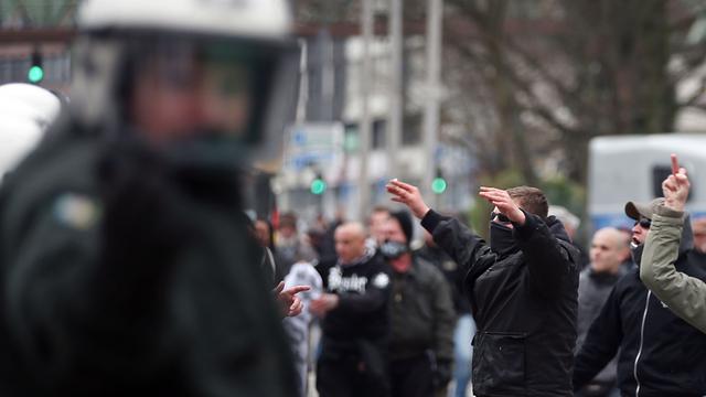 Mitglieder der Gruppe "Hooligans gegen Salafisten" und ein Polizist bei der Demonstration in Wuppertal.