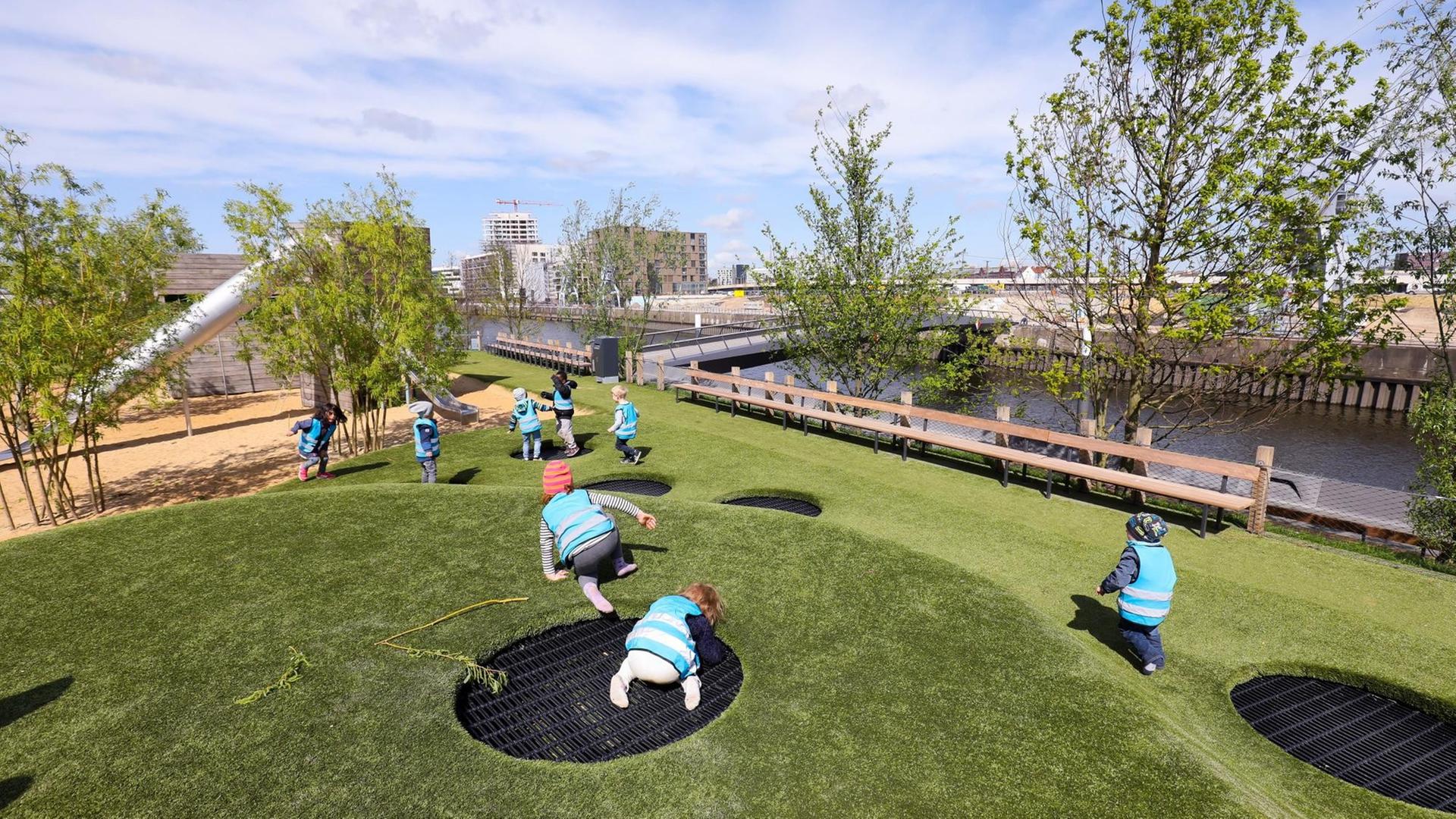 Kinder einer Kita aus der Hafencity toben auf dem Spielplatz im Baakenpark in der Hafencity in Hamburg. Der Baakenpark erhebt sich als 1,6 Hektar große, künstlich errichtete Halbinsel im Baakenhafen und ist das grüne Herzstück der östlichen HafenCity.