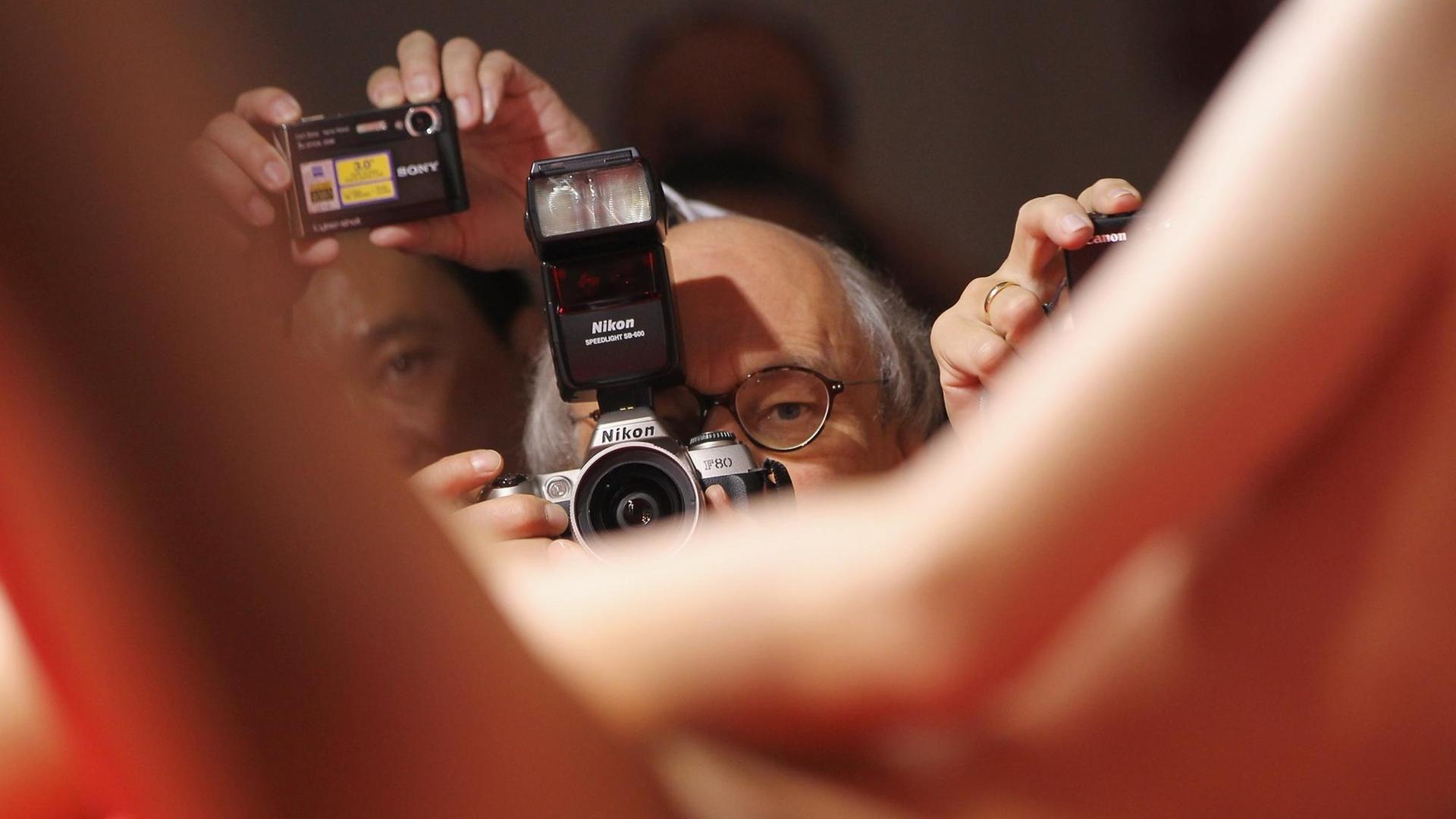 Eine Stripperin auf der Venus performt nackt, im Bildhintergrund richten Männer ihre Kameras auf sie. Eine Stripperin auf der Venus performt nackt, im Bildhintergrund richten Männer ihre Kameras auf sie.