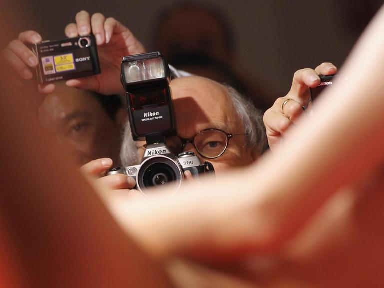 Eine Stripperin auf der Venus performt nackt, im Bildhintergrund richten Männer ihre Kameras auf sie.
