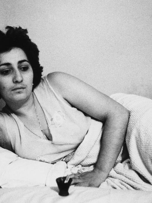 Eine Frau liegt auf einem Bett, ihre Zigarette in der Hand. Ohne Titel, aus der Serie "Georgien", 1982, von Helga Paris.