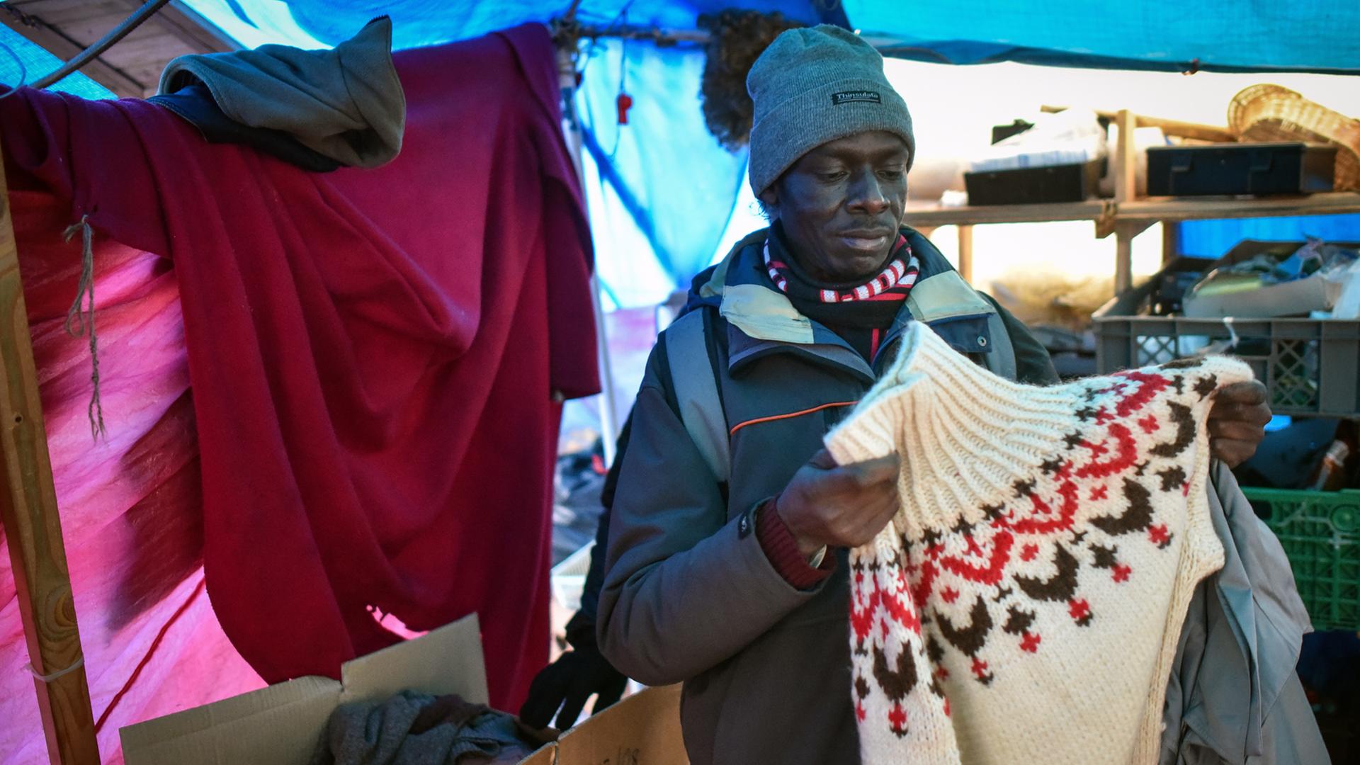 Ein Flüchtling begutachtet am 11.12.2014 in Hannover Winterkleidung in einem Zelt eines provisorischen Flüchtlingscamps. Ein Flüchtling begutachtet am 11.12.2014 in Hannover Winterkleidung in einem Zelt eines provisorischen Flüchtlingscamps.