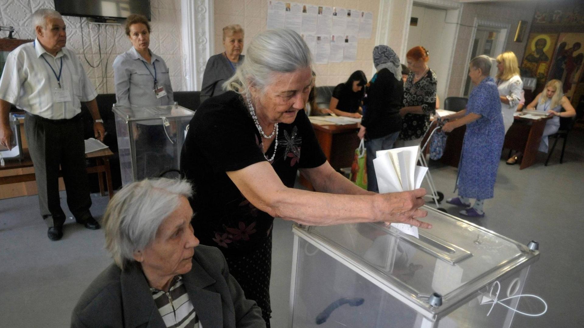 Eine ältere Frau wirft ihren Wahlzettel in eine Urne in Vinnytsia in der Ukraine Eine ältere Frau wirft ihren Wahlzettel in eine Urne in Vinnytsia in der Ukraine