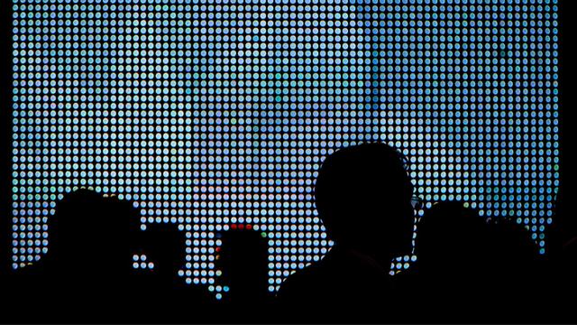 Die Schattenrisse von Messepublikum erscheinen vor den grell-blauen Leuchtdioden eines großen LED-Displays. Aufgenommen auf der Sicherheitsmesse Infosec in London am 28.04.2010. Foto: Maximilian Schönherr | Verwendung weltweit