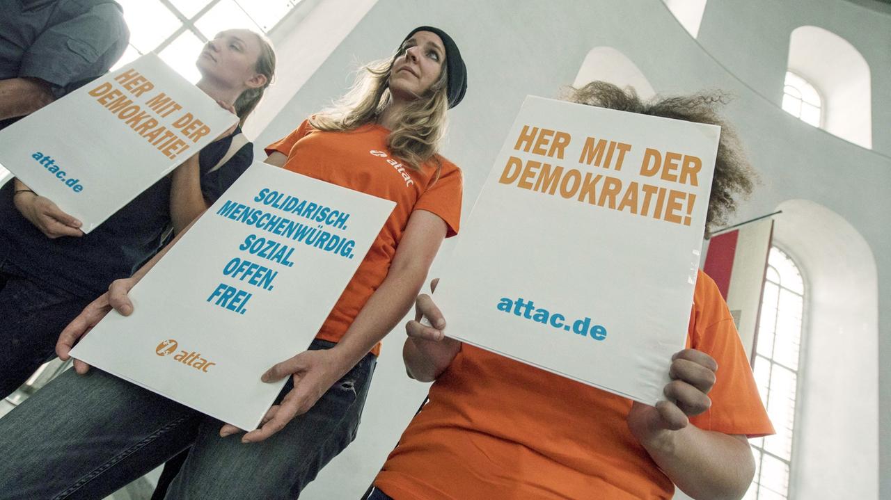 Attac-Aktivistinnen stehen mit Protestplakaten in der Paulskirche Attac-Aktivistinnen stehen mit Protestplakaten in der Paulskirche