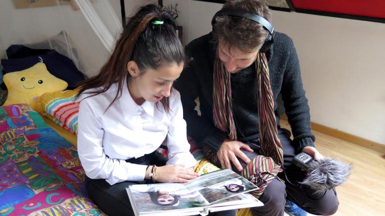 Christiana zeigt Reporter Manfred Götzke ihr Schulabschluss-Heft. Weil ihre Mutter zum Arbeiten nach Spanien gegangen ist, ist Christiana im Kinderheim 