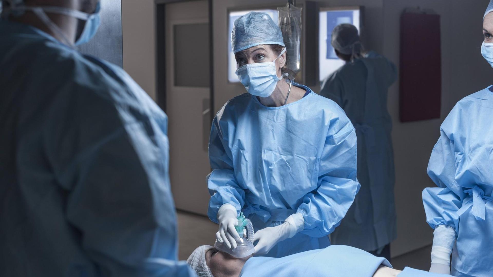 Ein Operationsteam im Krankenhaus. Eine Frau auf der Liege bekommt ein Beatmungsgerät aufgesetzt. Ein Operationsteam im Krankenhaus. Eine Frau auf der Liege bekommt ein Beatmungsgerät aufgesetzt.