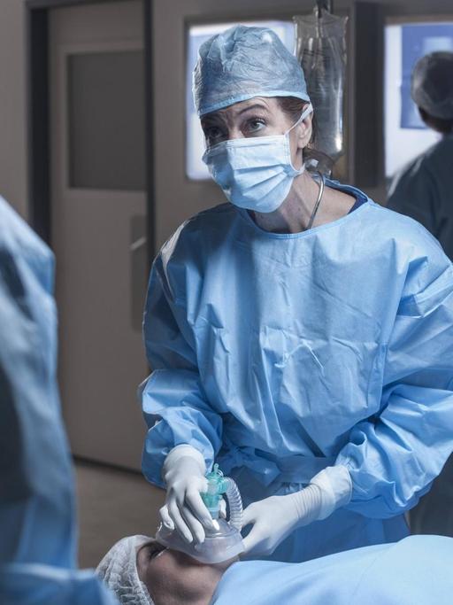 Ein Operationsteam im Krankenhaus. Eine Frau auf der Liege bekommt ein Beatmungsgerät aufgesetzt.