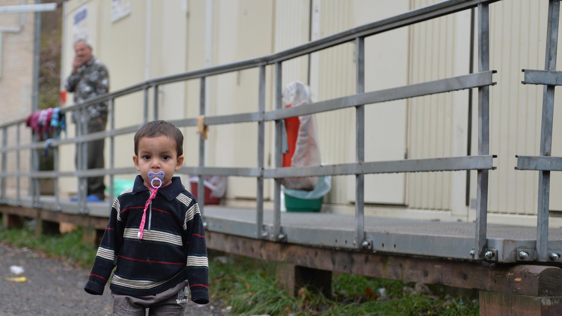 Ein Kleinkind steht am 21.11.2013 in Eisenberg (Thüringen) auf dem Gelände der Erstaufnahmestelle für Flüchtlinge und Asylbewerber vor Wohncontainern. Die Suche nach einer neuen Erstaufnahmestelle für Flüchtlinge in Thüringen gestaltet sich weiterhin schwierig. Es sei noch keine Entscheidung gefallen, sagte ein Sprecher des Innenministeriums der Nachrichtenagentur dpa in Erfurt. Ein Kleinkind steht am 21.11.2013 in Eisenberg (Thüringen) auf dem Gelände der Erstaufnahmestelle für Flüchtlinge und Asylbewerber vor Wohncontainern. Die Suche nach einer neuen Erstaufnahmestelle für Flüchtlinge in Thüringen gestaltet sich weiterhin schwierig. Es sei noch keine Entscheidung gefallen, sagte ein Sprecher des Innenministeriums der Nachrichtenagentur dpa in Erfurt.