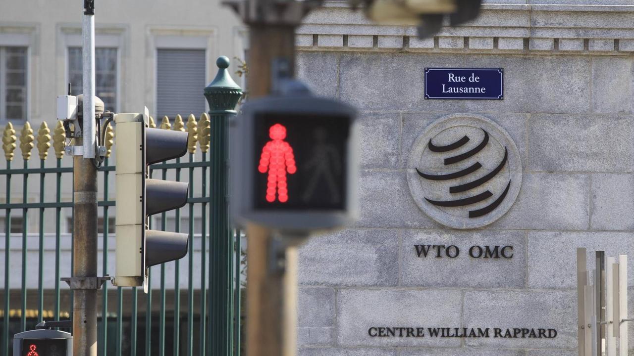Logo der Welthandelsorganisation WTO am Eingang zum WTO-Gebäude in Genf, im Vordergrund eine Ampel Logo der Welthandelsorganisation WTO am Eingang zum WTO-Gebäude in Genf, im Vordergrund eine Ampel