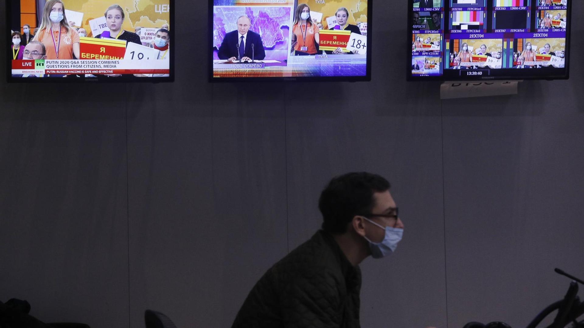 Ein Journalist sitz in einer Redaktion und schaut auf einen Computer. Im Hintergrund sind Bildschirme zu sehen. Ein Journalist sitz in einer Redaktion und schaut auf einen Computer. Im Hintergrund sind Bildschirme zu sehen.