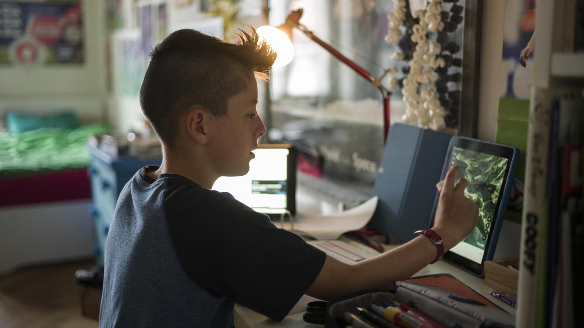 Ein Fünftklässler arbeitet zu Hause für die Schule. Er ist über sein iPad mit der Schule - den Lehrpersonen und den Mitschülerinnen seiner Klasse - verbunden. Ein Fünftklässler arbeitet zu Hause für die Schule. Er ist über sein iPad mit der Schule - den Lehrpersonen und den Mitschülerinnen seiner Klasse - verbunden.