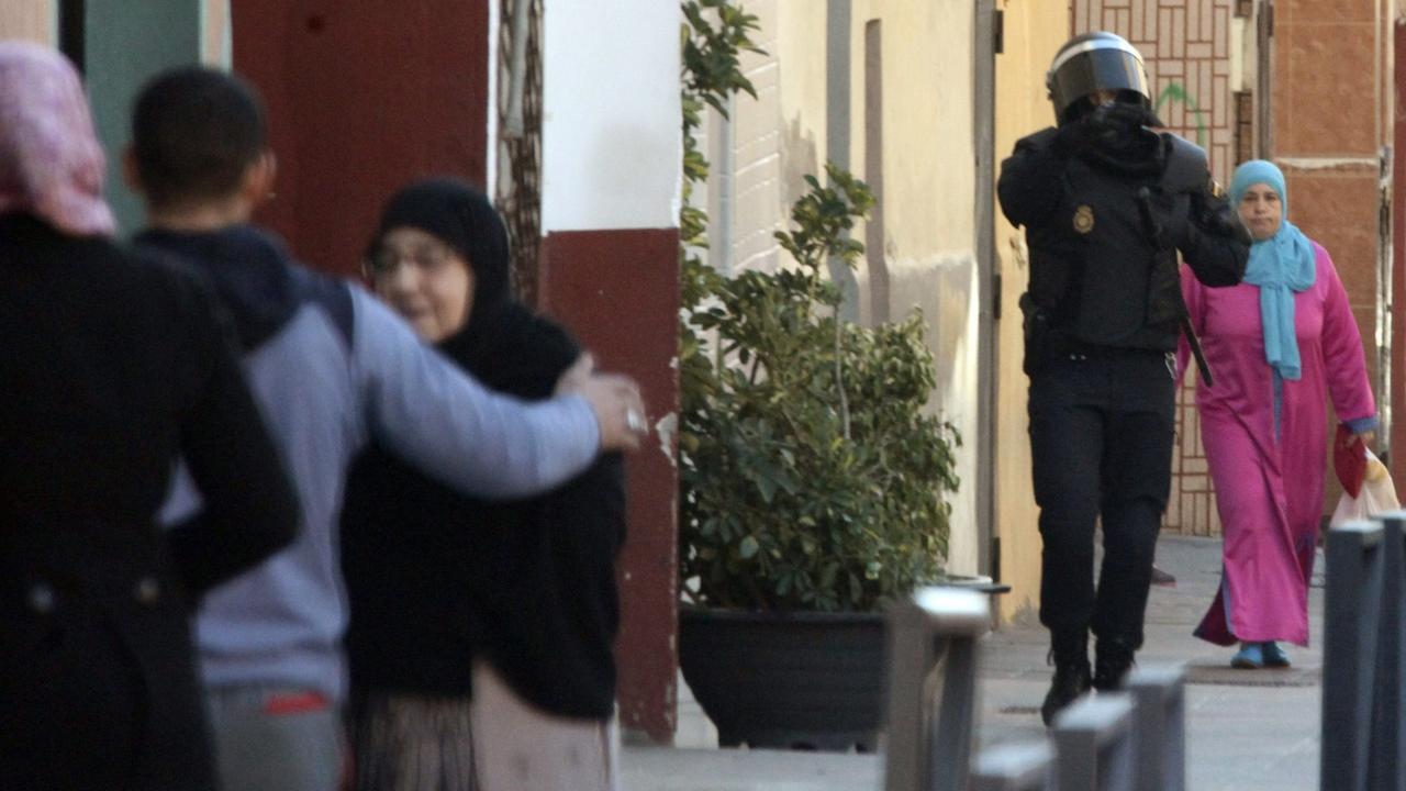 Ein Polizist läuft zwischen muslimischen Bewohnern nachdem die Polizei vier mutmaßliche Dschihadisten in El Principe, einem Randgebiet von Ceuta, am 24.01.2015 festgenommen hatte. Ein Polizist läuft zwischen muslimischen Bewohnern nachdem die Polizei vier mutmaßliche Dschihadisten in El Principe, einem Randgebiet von Ceuta, am 24.01.2015 festgenommen hatte.