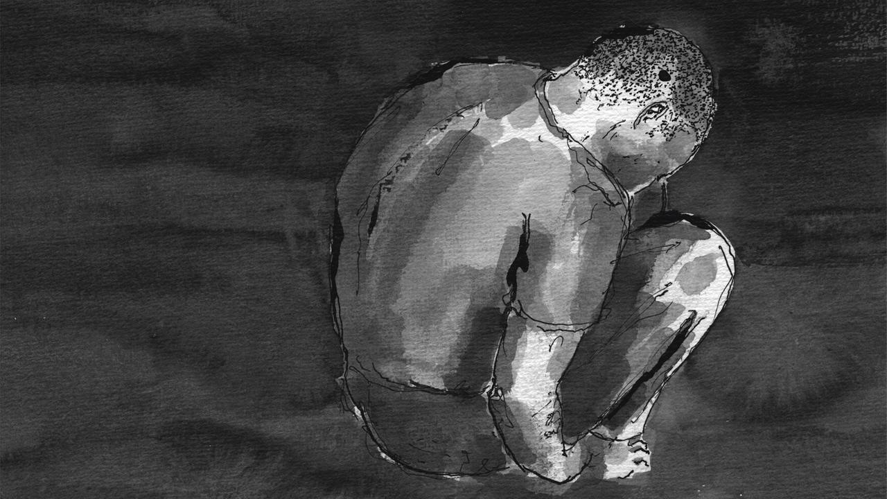 Ein Kauernder Jugendlicher in einer Gefängniszelle Ein Kauernder Jugendlicher in einer Gefängniszelle