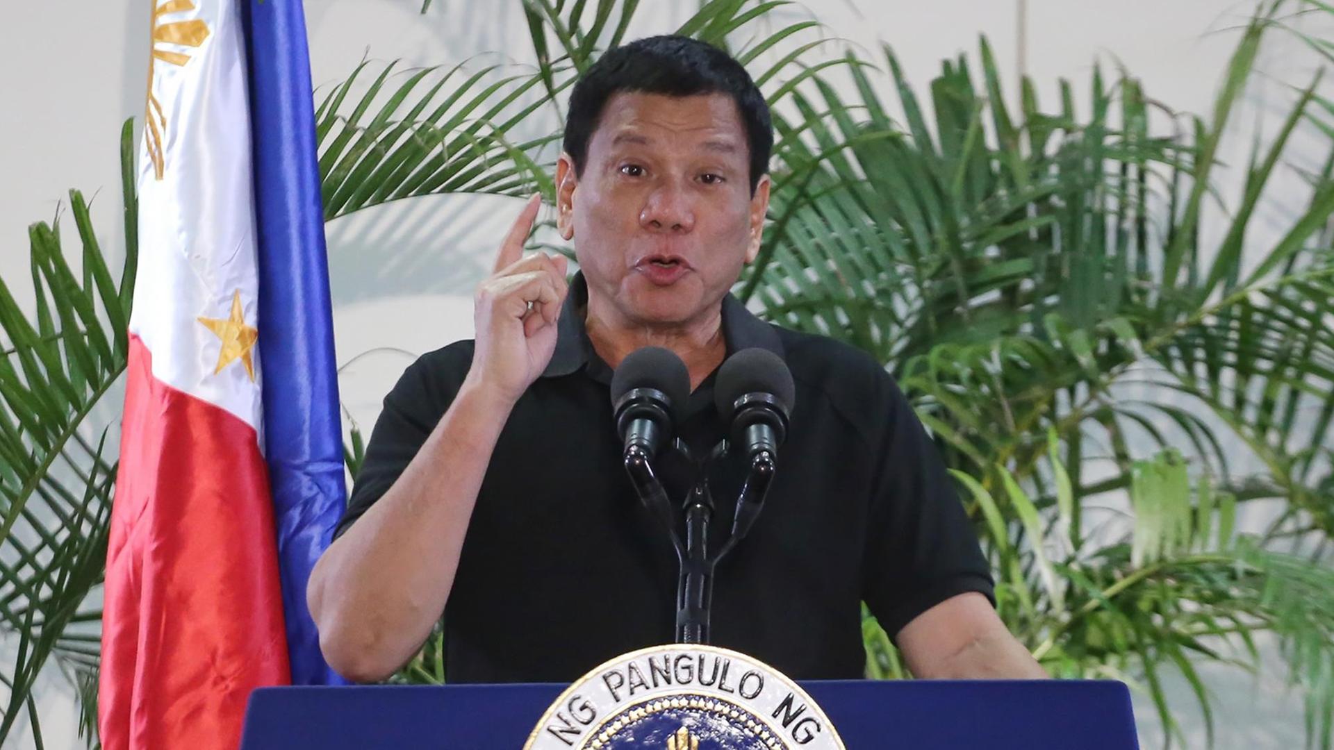 Duterte steht neben einer Flagge und hält eine Rede.