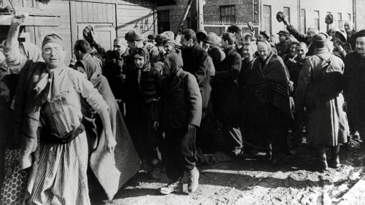 Überlebende des Konzentrationslagers Auschwitz verlassen das Lager und machen dabei Siegesgesten. Überlebende des Konzentrationslagers Auschwitz verlassen das Lager und machen dabei Siegesgesten.