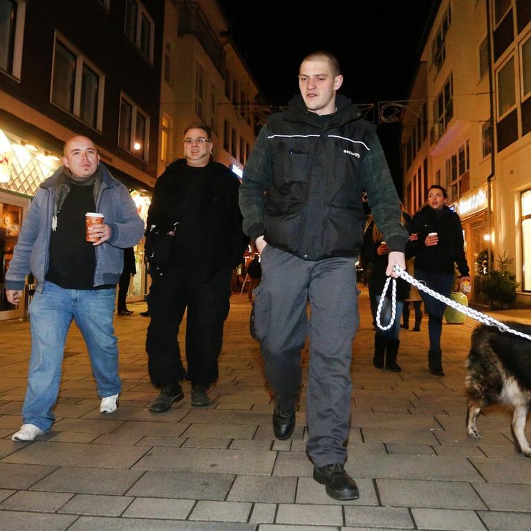 Sympathisanten einer Düsseldorfer Bürgerwehr ziehen im Dunkeln mit einem Hund durch die Altstadt.