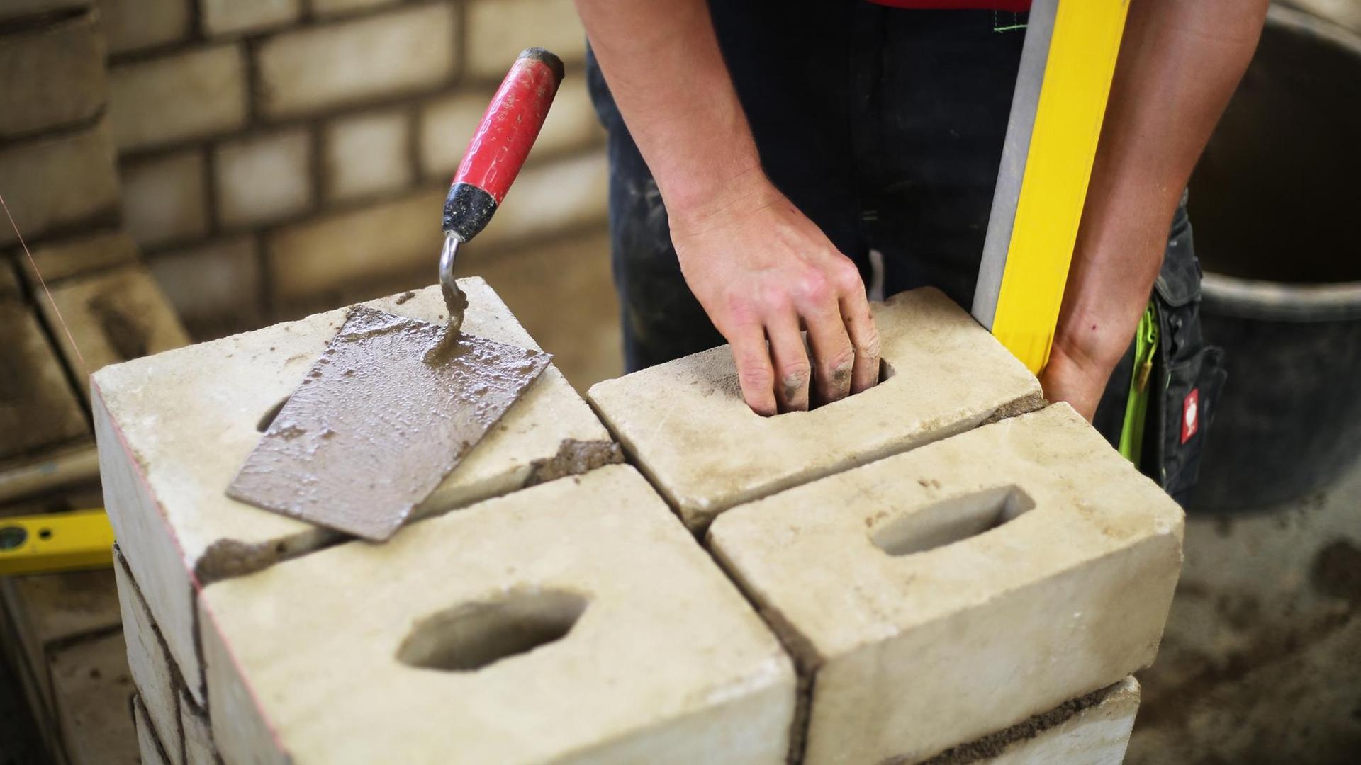 Ein Auszubildender arbeitet an einer Mauer. Ein Auszubildender arbeitet an einer Mauer.