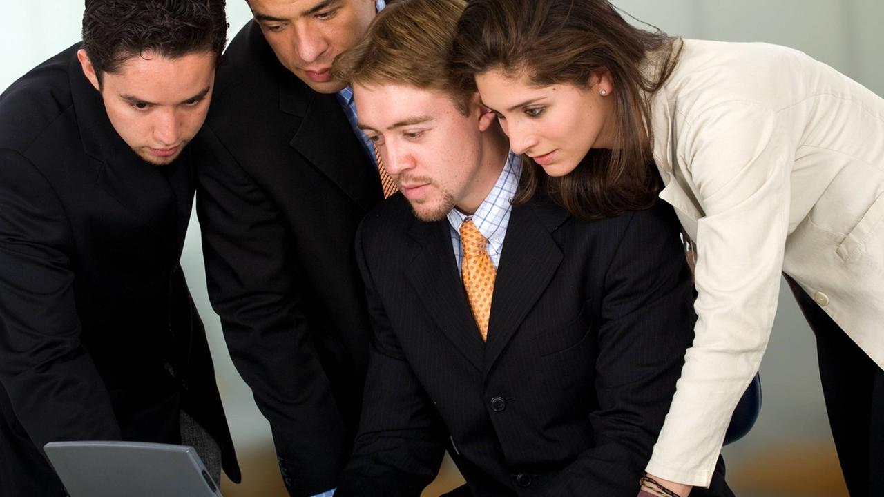 Ein Mann und eine Frau in Business-Look beugen sich gemeinsam über einen Laptop-Computer Ein Mann und eine Frau in Business-Look beugen sich gemeinsam über einen Laptop-Computer