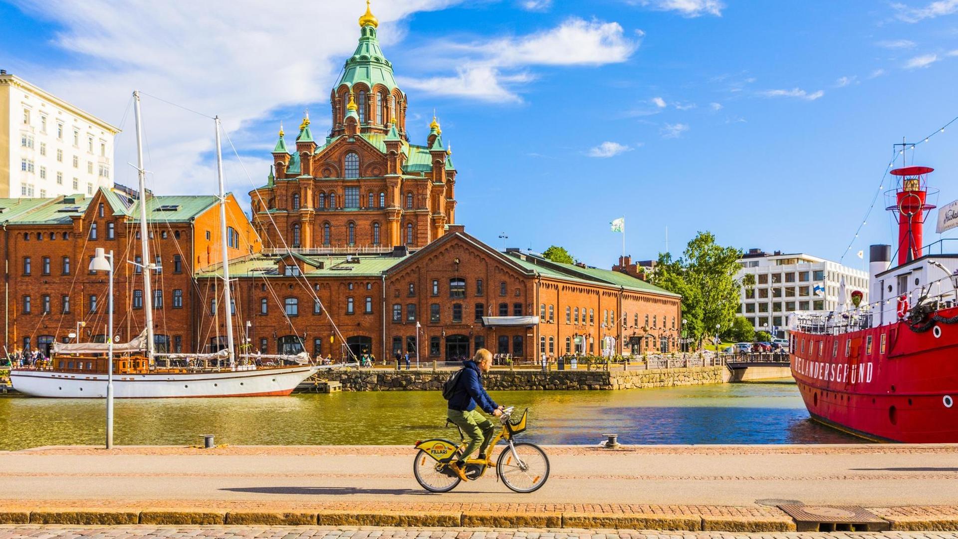 Ein Fahrradfaher vor der Uspenski-Kathedrale in der finnischen Hauptstadt Helsinki. Ein Fahrradfaher vor der Uspenski-Kathedrale in der finnischen Hauptstadt Helsinki.