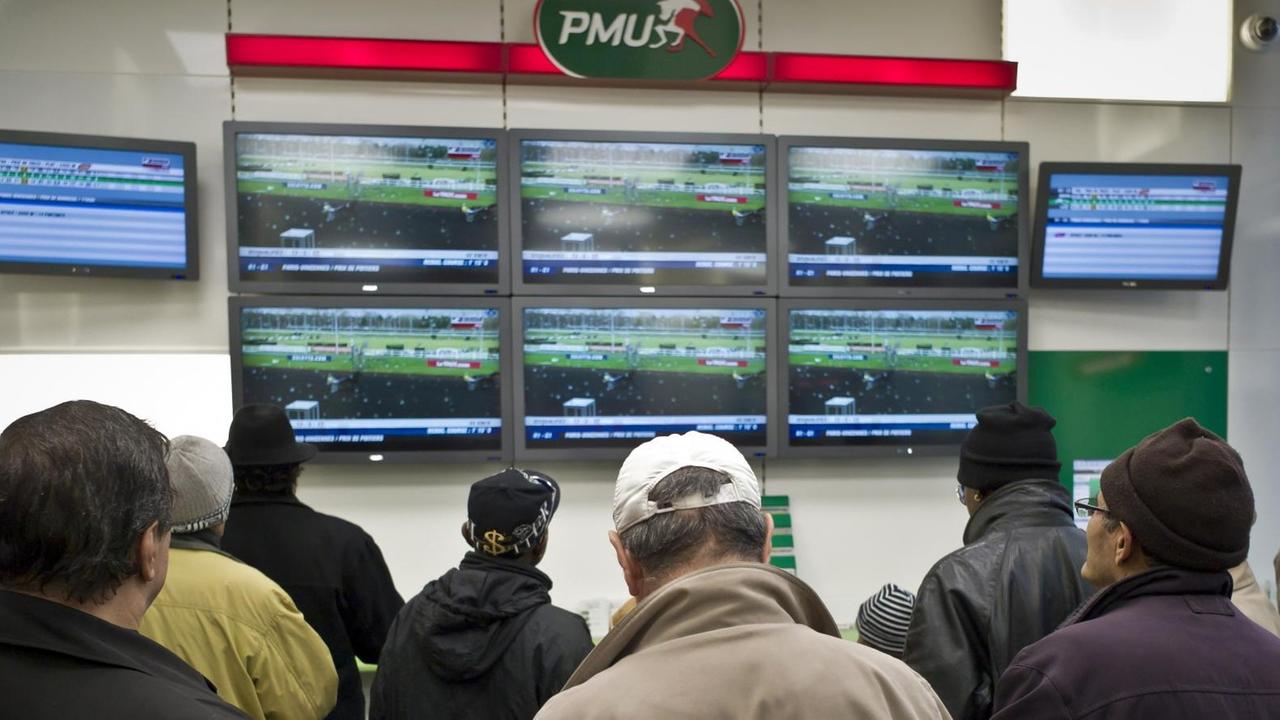 Spieler verfolgen ein Pferderennen in einem Wettbüro des französischen Anbieters PMU in Lyon