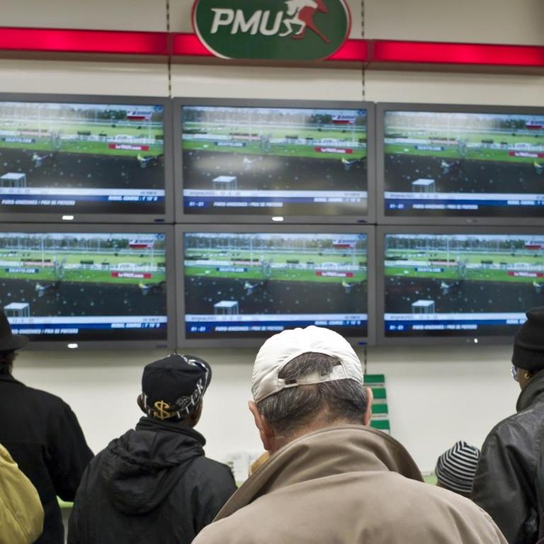 Spieler verfolgen ein Pferderennen in einem Wettbüro des französischen Anbieters PMU