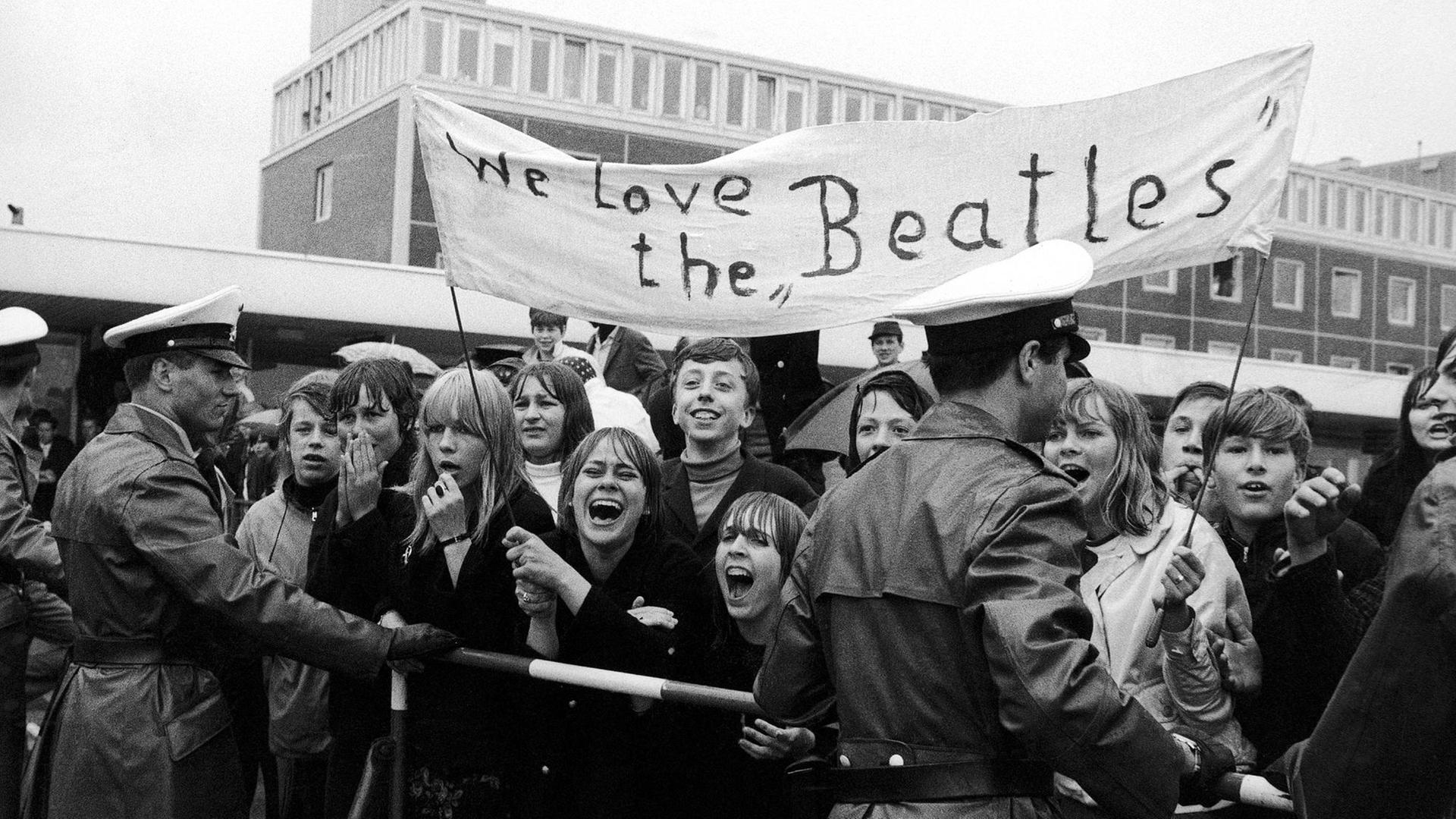 Beatlesfans tragen mit der Aufschrift "We love the Beatles". Beatlesfans tragen mit der Aufschrift "We love the Beatles".