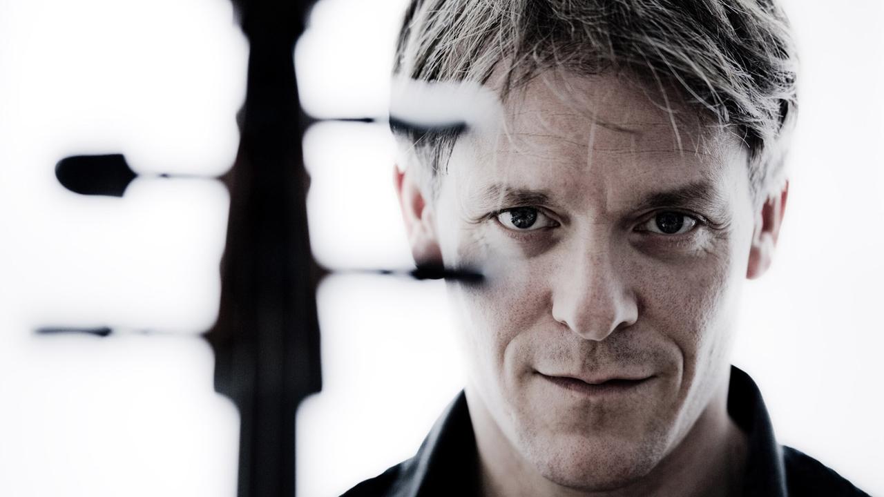 Der Cellist Alban Gerhardt blickt an den Wirbeln seines Cellos vorbei in die Kamera. Der Cellist Alban Gerhardt blickt an den Wirbeln seines Cellos vorbei in die Kamera.