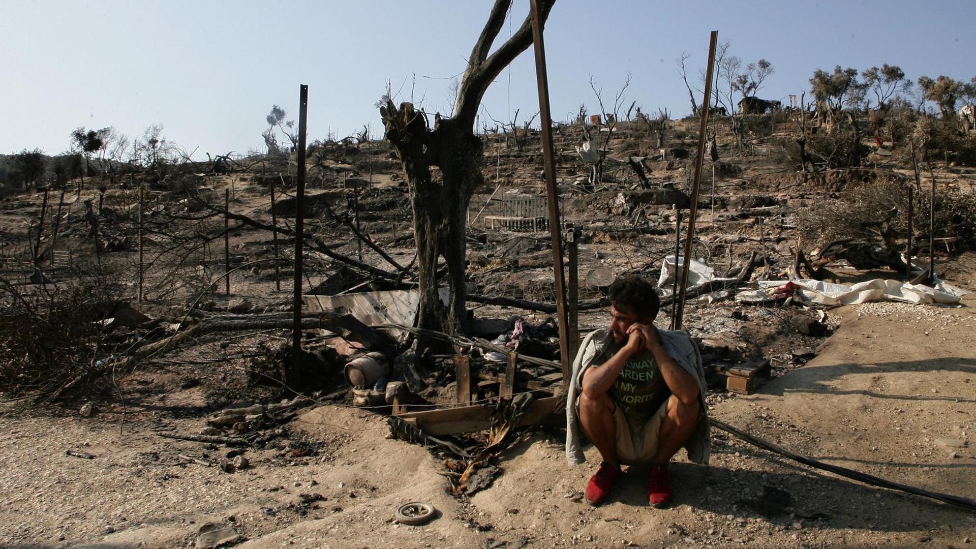 Ein Flüchtling sitzt vor den Überresten des abgebrannten Flüchtlingslagers Moria, auf der griechischen Insel Lesbos.