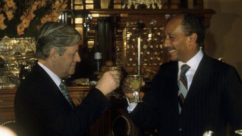 Helmut Schmidt und Muhammar Anwar as-Sadat stoßen ihre Gläser an und lachen