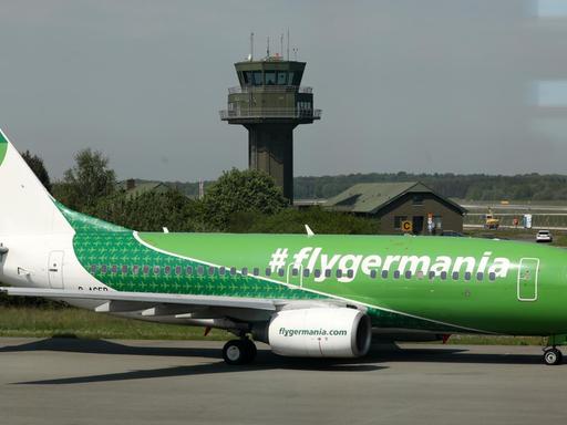 Ein grünes Flugzeug mit der Aufschrift #flygermania am Flughafen Rostock-Laage