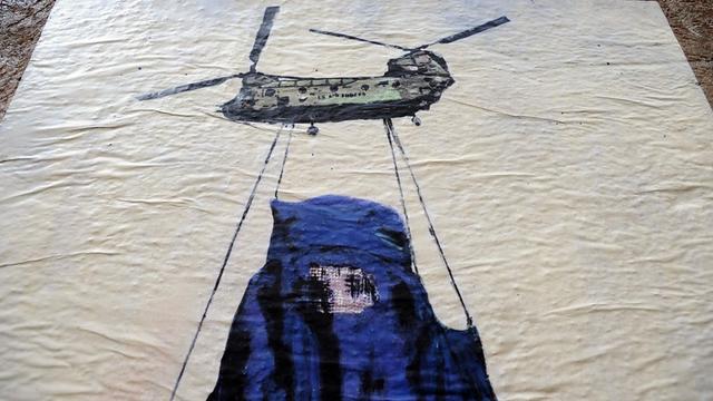 Ein Wandbild des Künstlers Harry Greb in Rom zeigt einen Hubschrauber, der eine Frau in einer Burka an Seilen trägt.