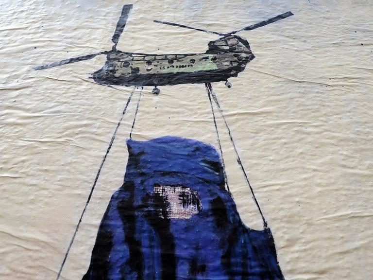 Ein Wandbild des Künstlers Harry Greb in Rom zeigt einen Hubschrauber, der eine Frau in einer Burka an Seilen trägt.