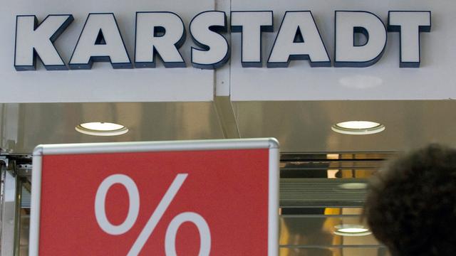 Eine Passantin geht am Dienstag (08.06.vor dem Karstadt-Warenhaus in Münster an einem Plakat mit dem Aufdruck "Reduziert" vorbei.
