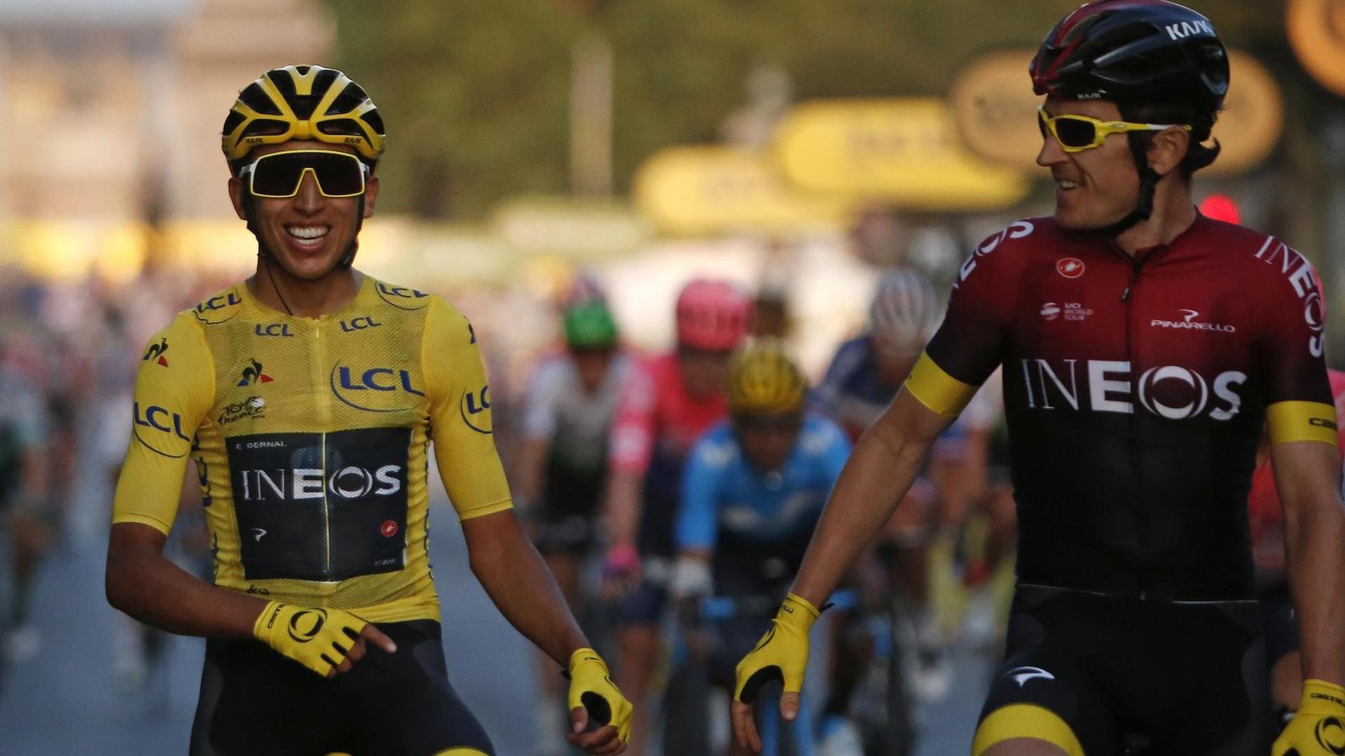 Egan Bernal und Geraint Thomas auf ihren Rädern. Sie lachen beide. Egan Bernal und Geraint Thomas auf ihren Rädern. Sie lachen beide.