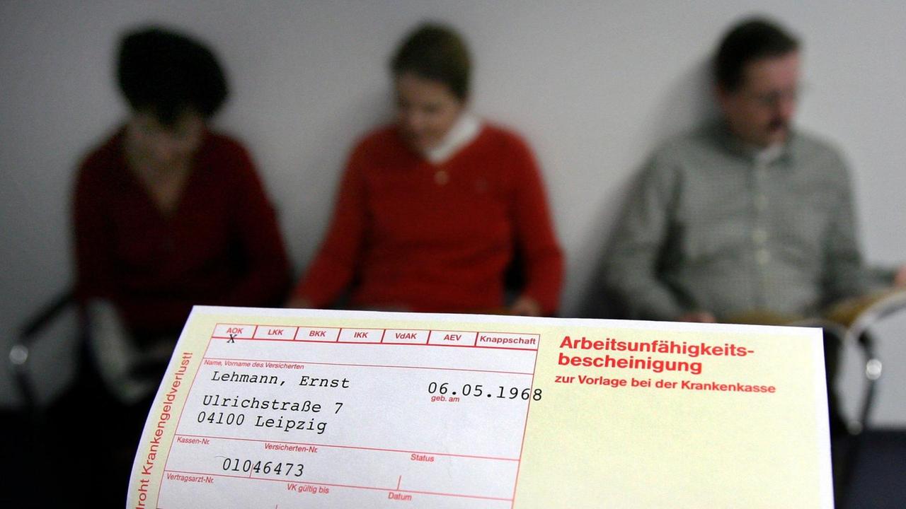 Ein Krankenschein wird vor eine Gruppe von Patienten gehalten (gestelltes Illustrationsfoto) Ein Krankenschein wird vor eine Gruppe von Patienten gehalten (gestelltes Illustrationsfoto)