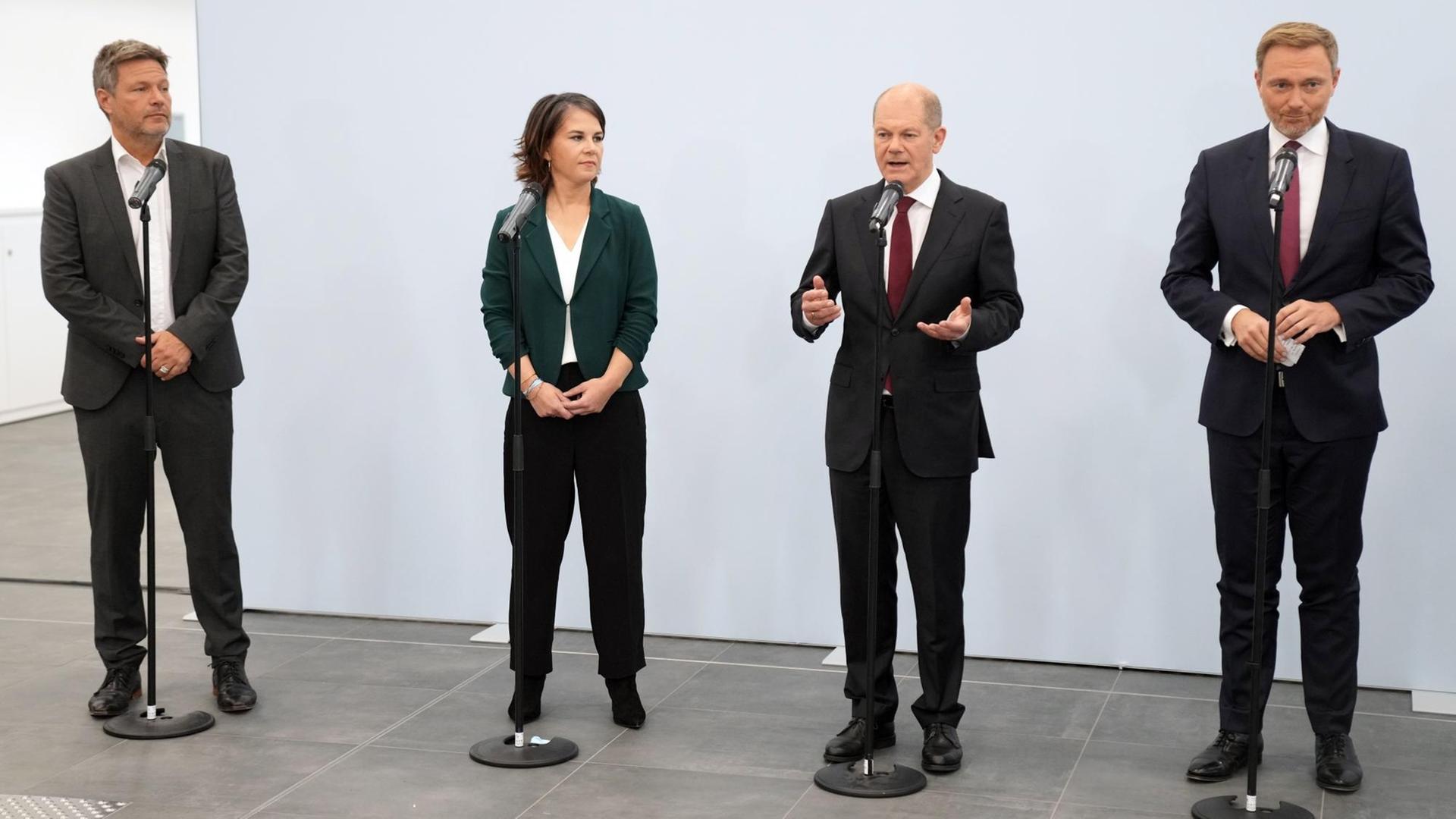 Robert Habeck und Annalena Baerbock von den Grünen, Olaf Scholz von der SPD und Christian Lindner von der FDP stehen vor Mikrofonen.