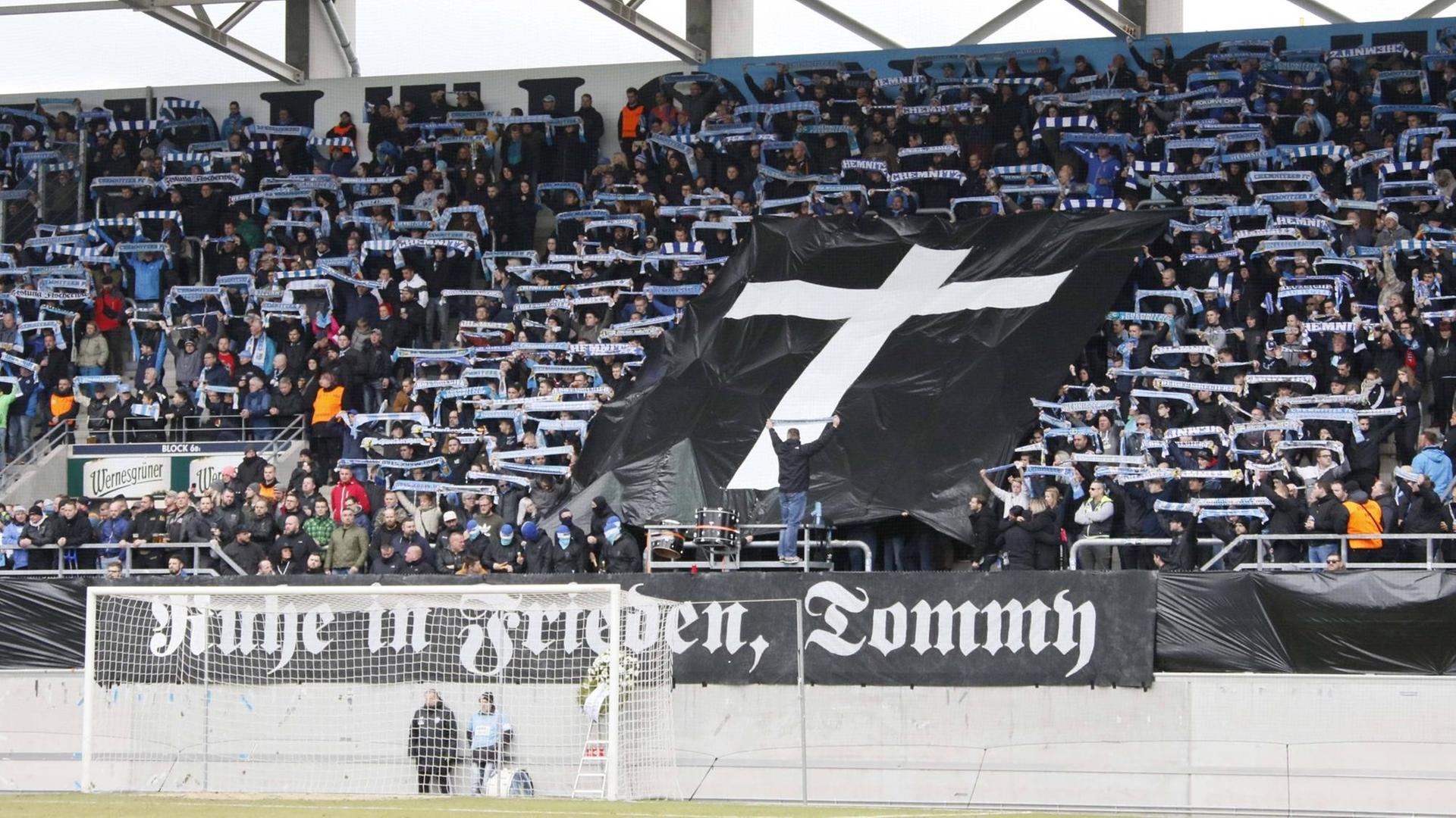 Im Fanblock des FC Chemnitz ist eine schwarze Fahne mit einem Kreuz aufgespannt. Darunter auf einem weiteren Banner "Ruhe in Frieden, Tommy" Im Fanblock des FC Chemnitz ist eine schwarze Fahne mit einem Kreuz aufgespannt. Darunter auf einem weiteren Banner "Ruhe in Frieden, Tommy"