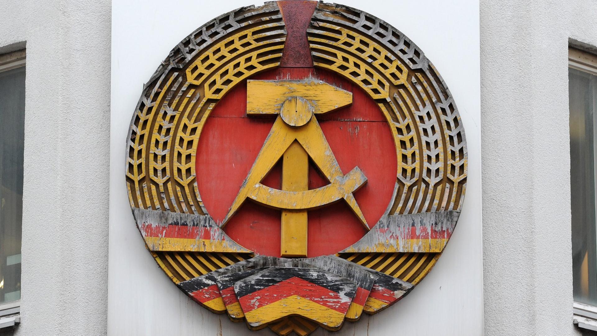 Ein DDR-Emblem hängt an einer Wand.