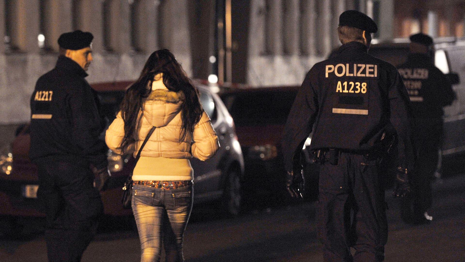 Polizisten begleiten bei einem Polizeieinsatz mit Durchsuchungen am 08.11.2013 in der Kurfürstenstraße in Berlin eine Frau zu einem Kontrollpunkt. Polizisten begleiten bei einem Polizeieinsatz mit Durchsuchungen am 08.11.2013 in der Kurfürstenstraße in Berlin eine Frau zu einem Kontrollpunkt.