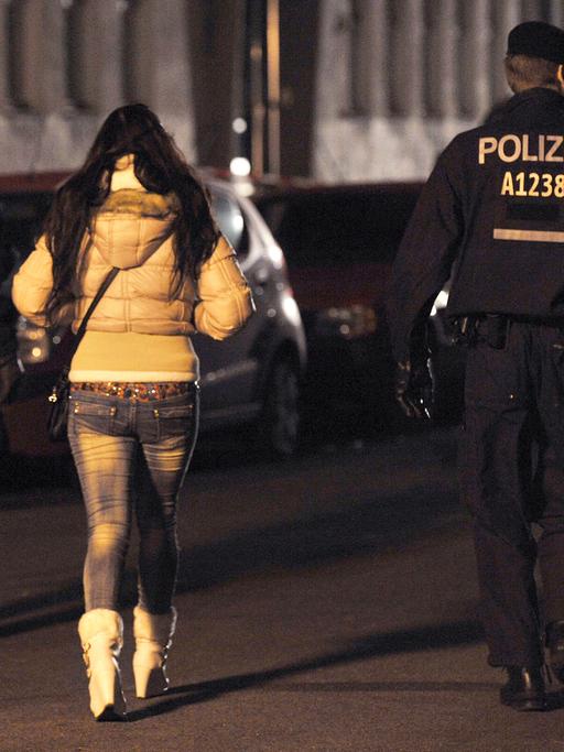 Polizisten begleiten bei einem Polizeieinsatz mit Durchsuchungen am 08.11.2013 in der Kurfürstenstraße in Berlin eine Frau zu einem Kontrollpunkt.