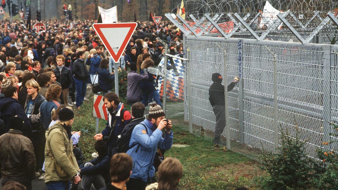 Während einer Demonstration gegen Atomenergie und für die Stilllegung der Atomfabriken Nukem und Alkem in Hanau am 8.11.1986 haben sich Demonstrationsteilnehmer vor dem mit Stacheldraht gesicherten Sperrzaun der Nuklearfabriken versammelt.