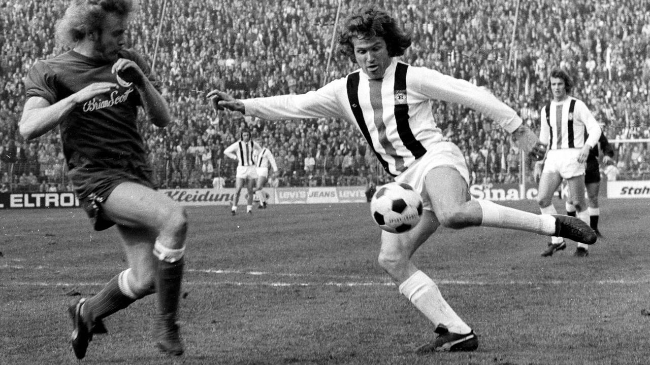 Im Spiel Borussia Mönchengladbach gegen den MSV Duisburg am 23. März 1974 schießt Jupp Heynckes, bevor vor Werner Schneider vom MSV ihn daran hindern kann.