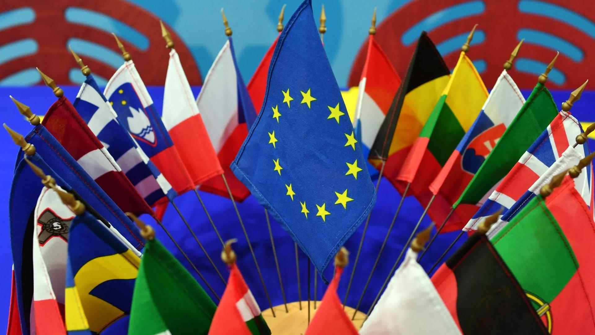 Sie sehen die Flaggen der Mitgliedsstaaten der EU, zusammen mit der EU-Flagge auf einem Tisch. Sie sehen die Flaggen der Mitgliedsstaaten der EU, zusammen mit der EU-Flagge auf einem Tisch.