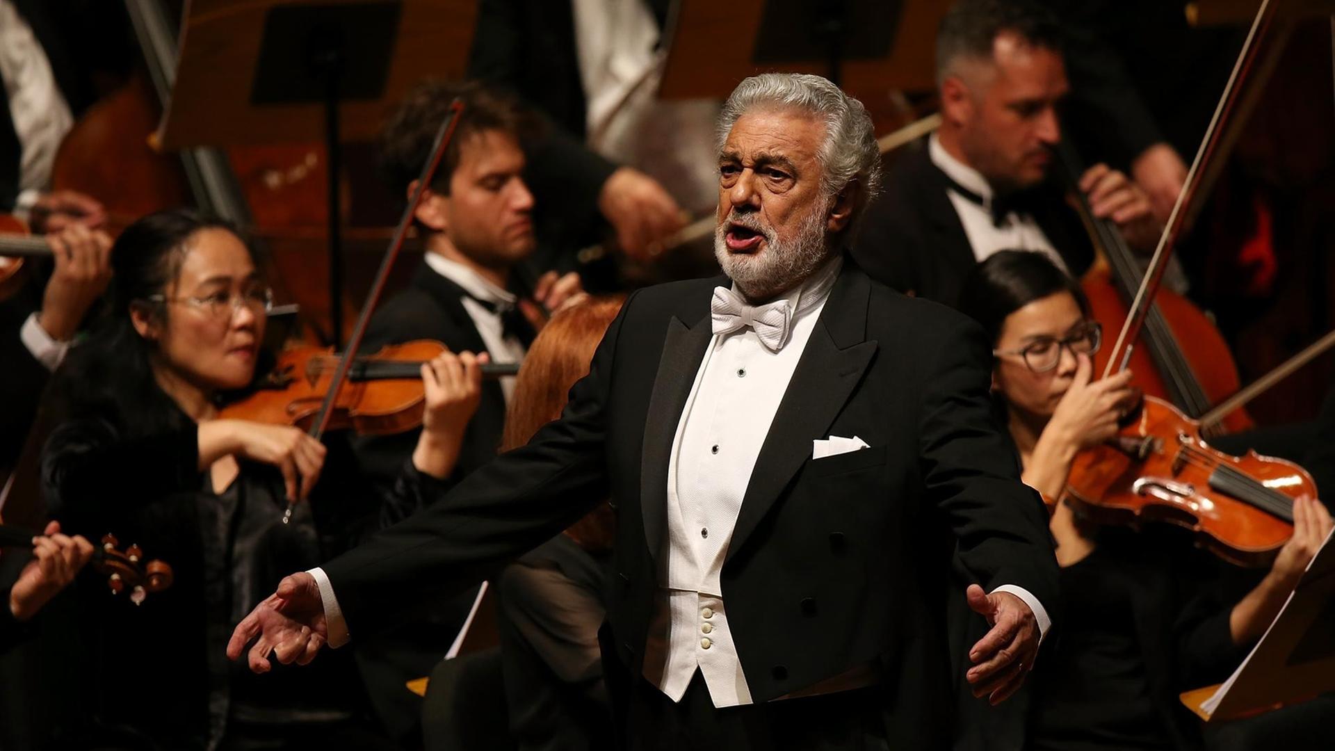 Placido Domingo steht bei einer Nabucco Aufführung vor dem Orchester und singt.